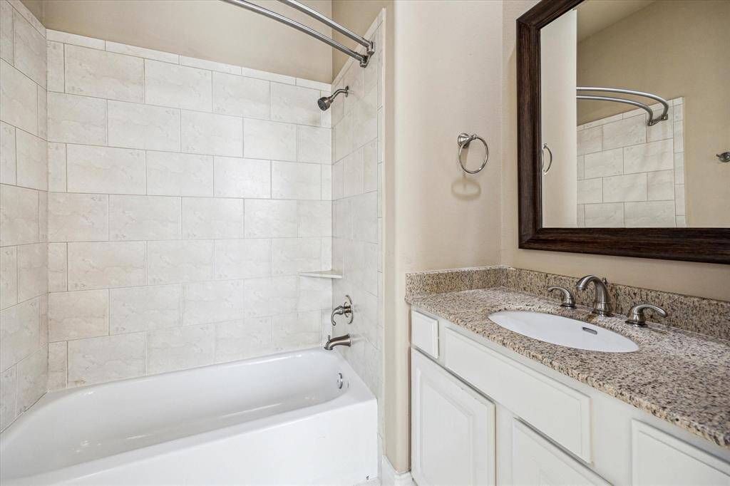 Ample-sized en-suite bathroom for the third-floor secondary bedroom, featuring a bath/shower combo, granite countertop, and a framed mirror above the vanity. The neutral color palette adds to the clean, timeless feel of the space.