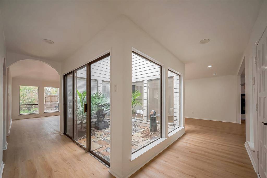 This home features a bright, open hallway and large windows overlooking a central atrium with plants, creating a serene indoor-outdoor feel.