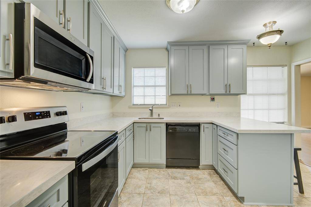 Elegant kitchen showcasing soft neutral cabinetry, polished quartz surfaces, and premium stainless steel appliances.