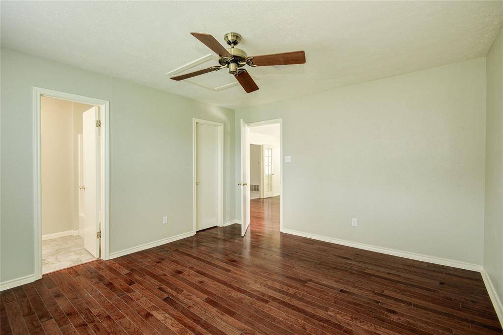 Spacious downstairs primary retreat with large window overlooking the side yard and rich hardwood floors.