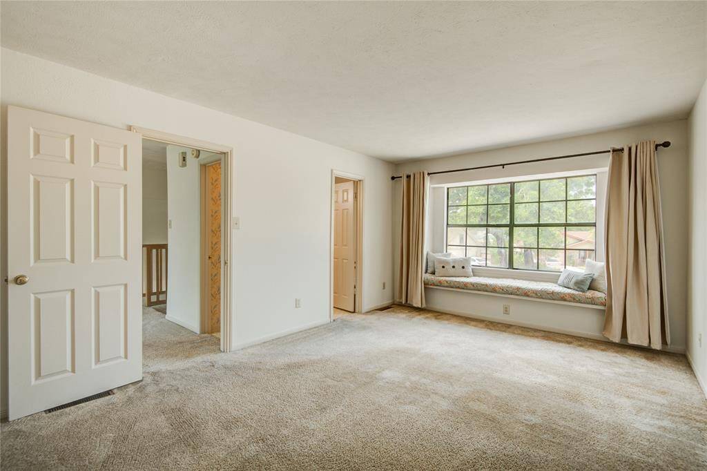 Second view of the upstairs primary suite, offering a glimpse into the adjoining game room and ensuite bath access."
