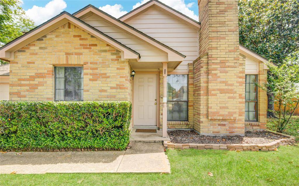A charming front entry with a classic brick elevation, neatly trimmed hedge, and a clean landscaping bed—ready for your personal touch.