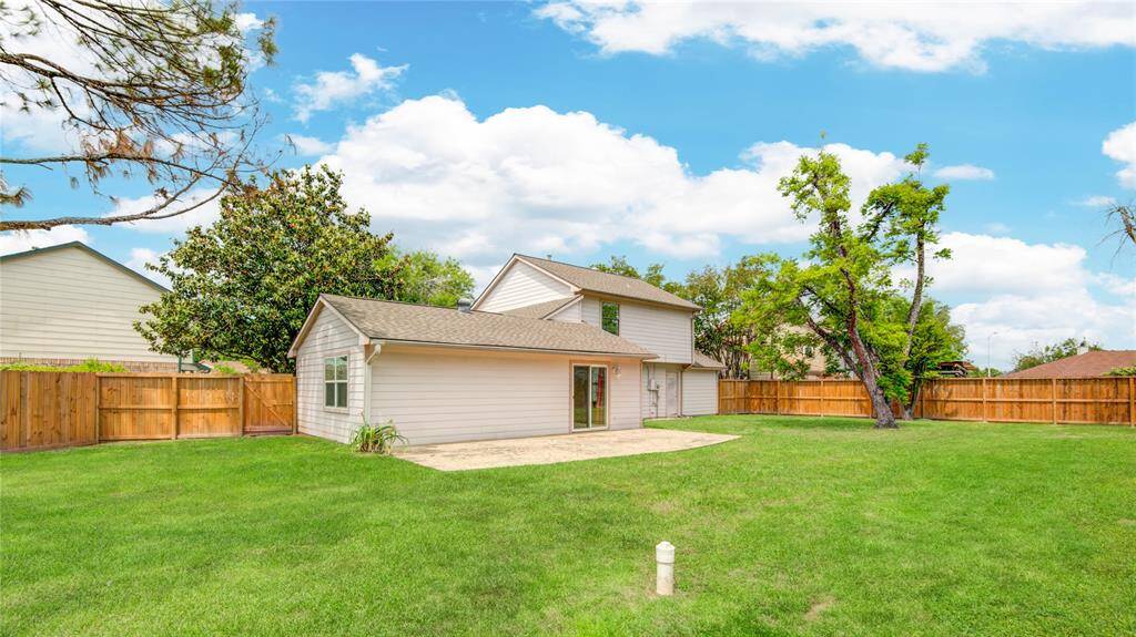 Sweeping view of the spacious backyard with a patio and mature trees, ideal for outdoor gatherings or quiet evenings.