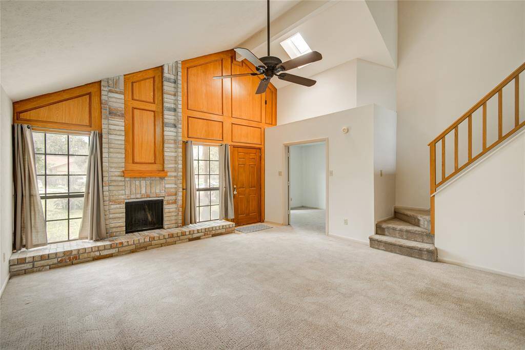 Soaring ceilings, a striking brick fireplace, and rich wood accents set the tone in this bright and spacious living area, complete with skylights and abundant natural light.