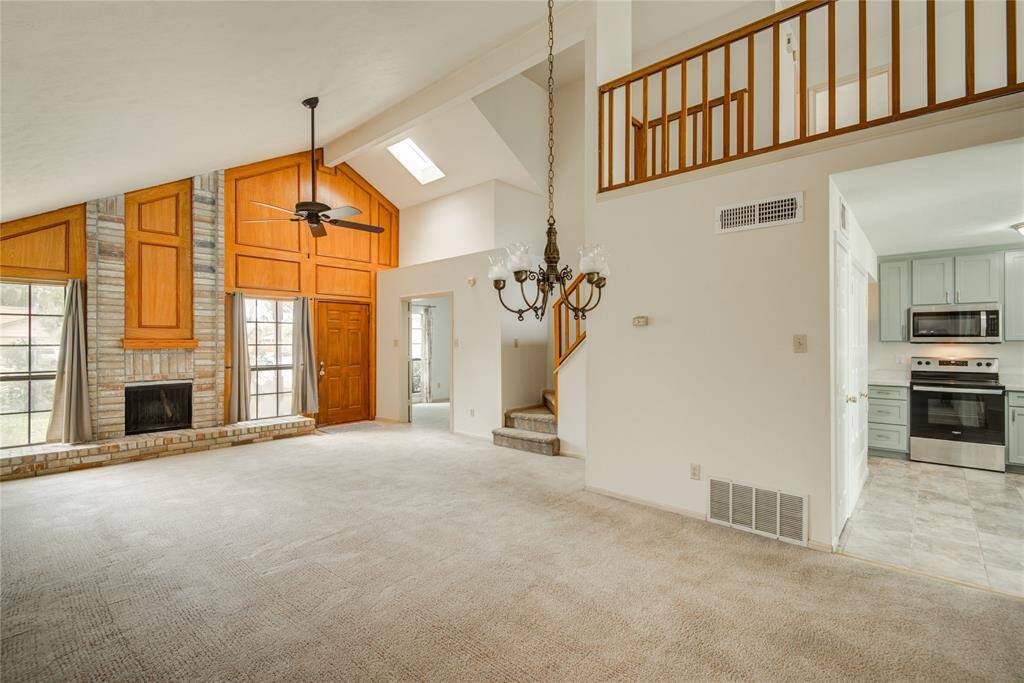 This expansive living space welcomes you with vaulted ceilings, a dramatic brick fireplace, and an open layout that flows effortlessly into the kitchen and dining areas.