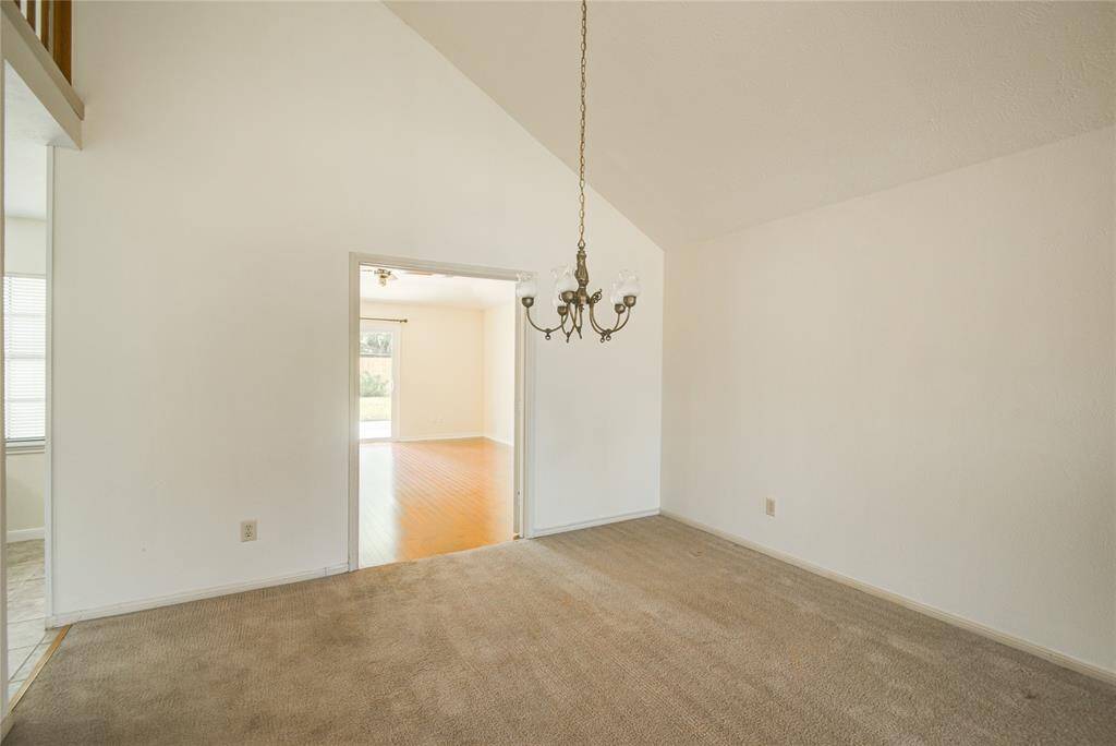 Spacious dining area with vaulted ceilings and a charming chandelier, opening directly into the family room.
