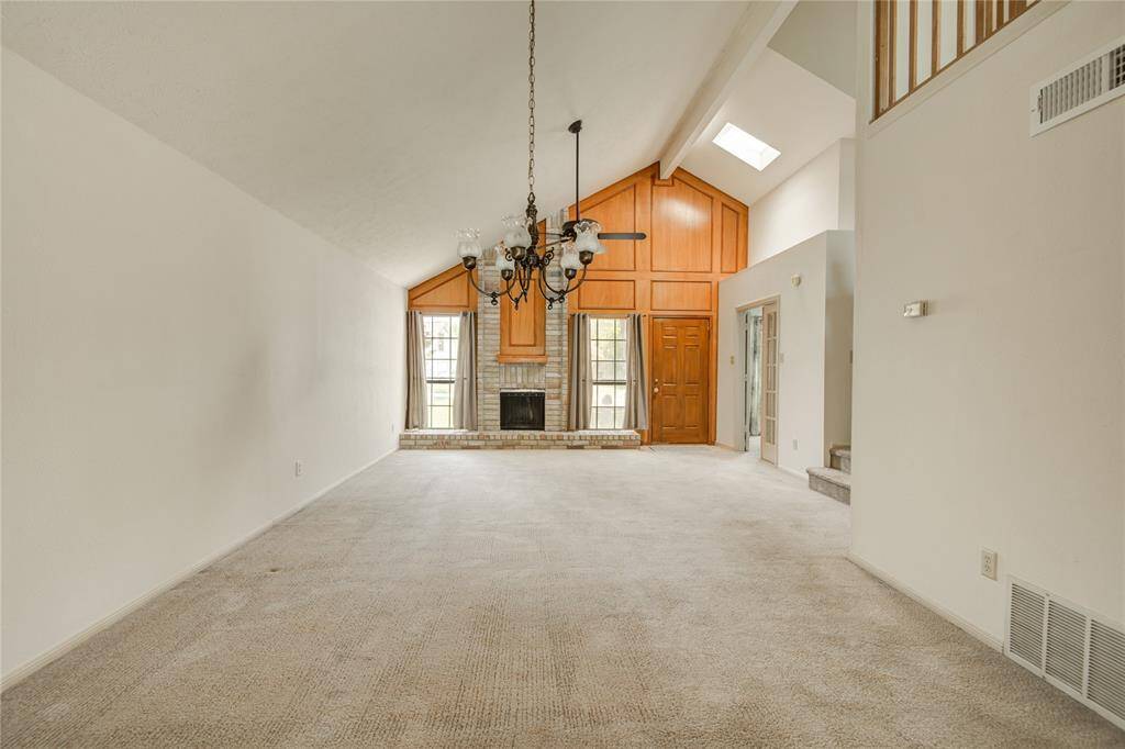 Elegant formal living room with vaulted ceiling, cozy fireplace, and natural light pouring in through tall front-facing windows.