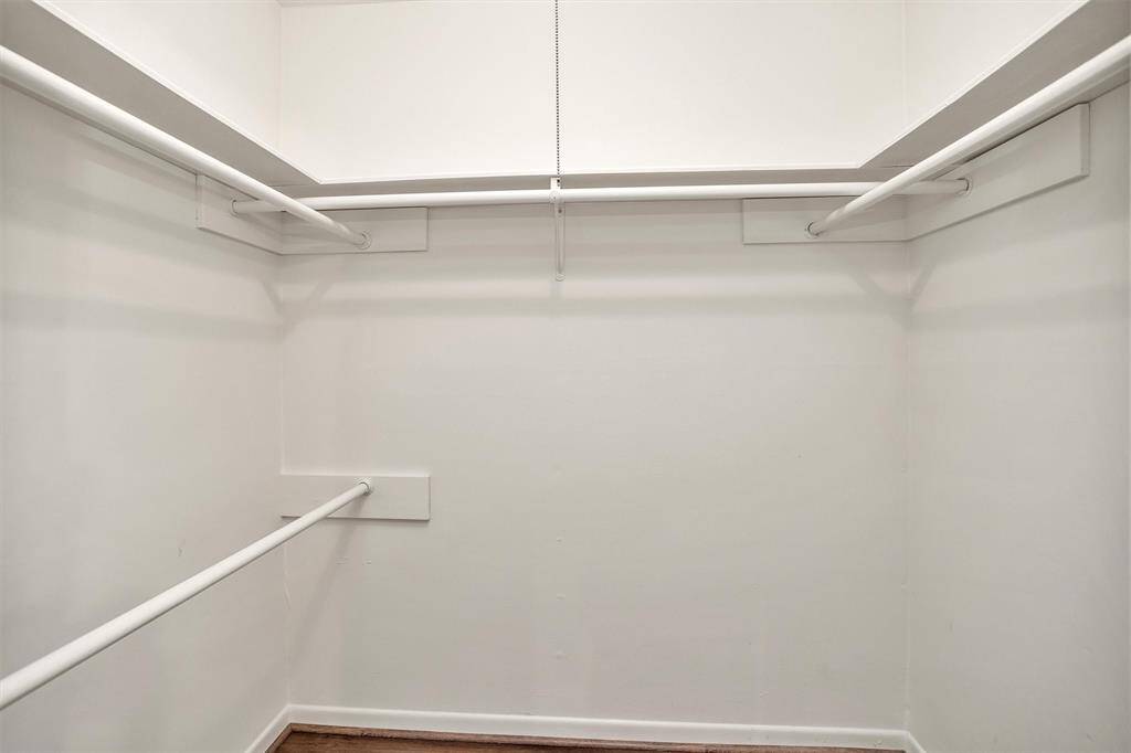 The Primary Walk-in Closet features built-in shelves and clothing racks for easy organization and storage.
