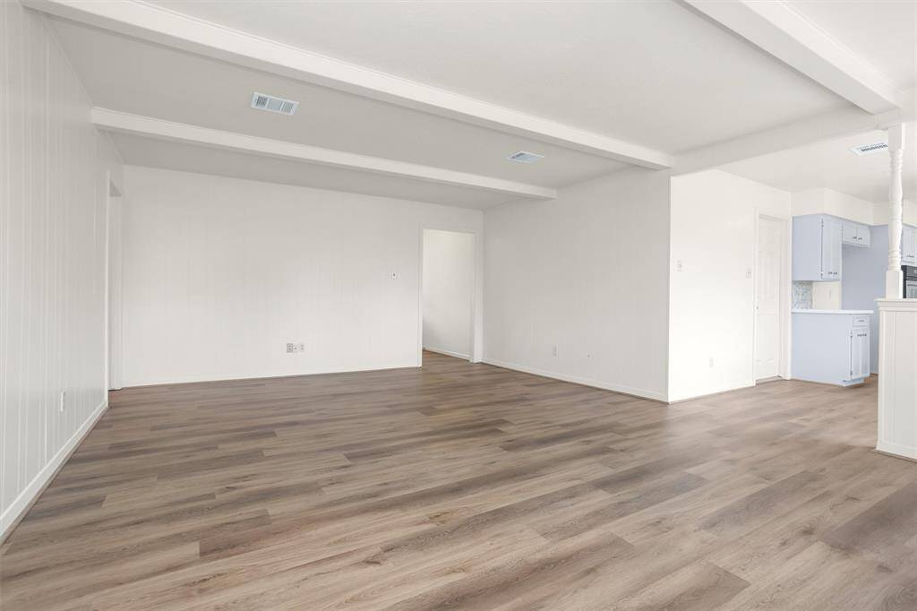 The sun-filled Family Room features a lovely brick fireplace & charming ceiling beams.