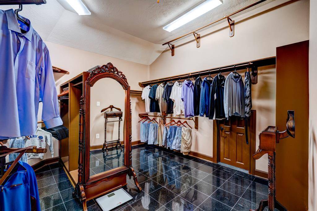 High ceilings, built-ins, and hanging bars offer multiple organizational possibilities in the master walk-in closet.