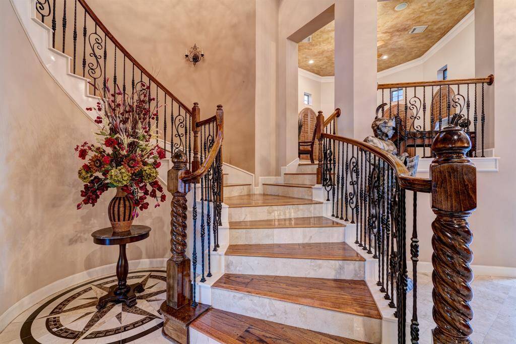 Evoking early Hollywood vibes, the front staircase features gorgeous millwork, black wrought iron spindles, and stunning hardwood treads.