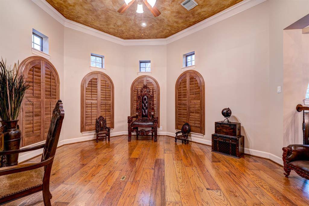 Plantation shutters, high ceilings, hardwood floors, and crown molding make for a sophisticated office/study with masculine elements.
