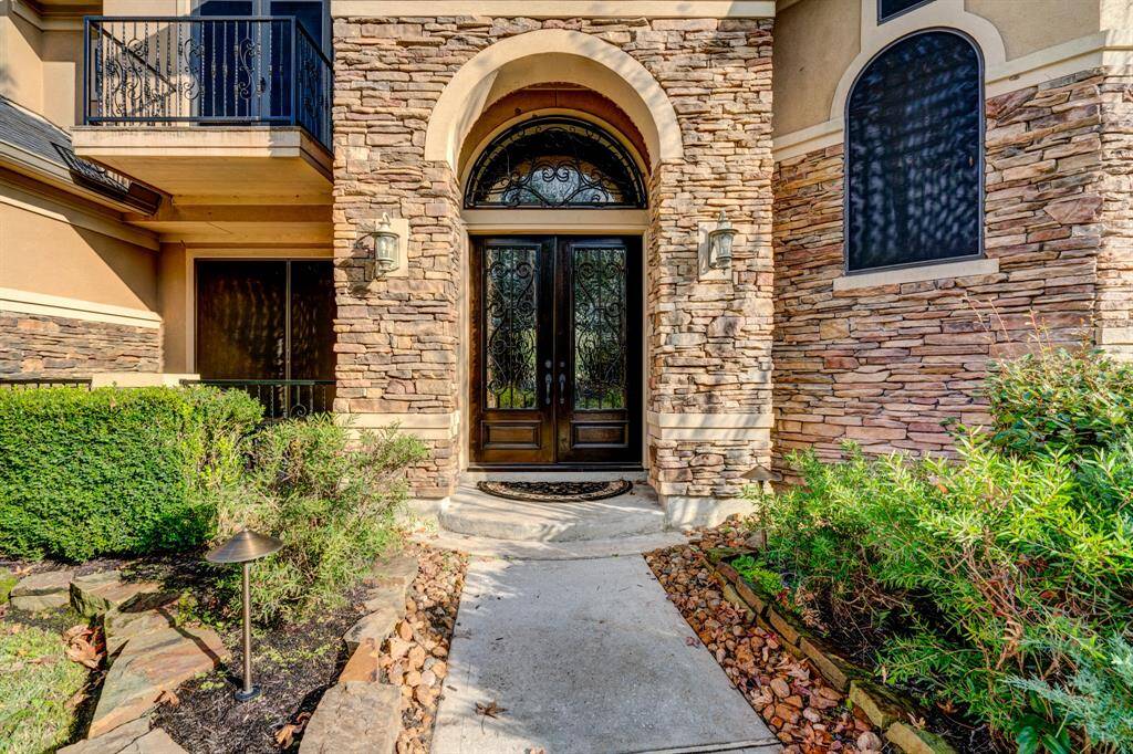 Stone exterior detailing, luscious bushes, and smooth river rocksadorn the front of the home in a culmination of natural splendor. Double iron front doors add anunderstated and bucolic element to the design, as the arched frame contributes a luxurious touch.