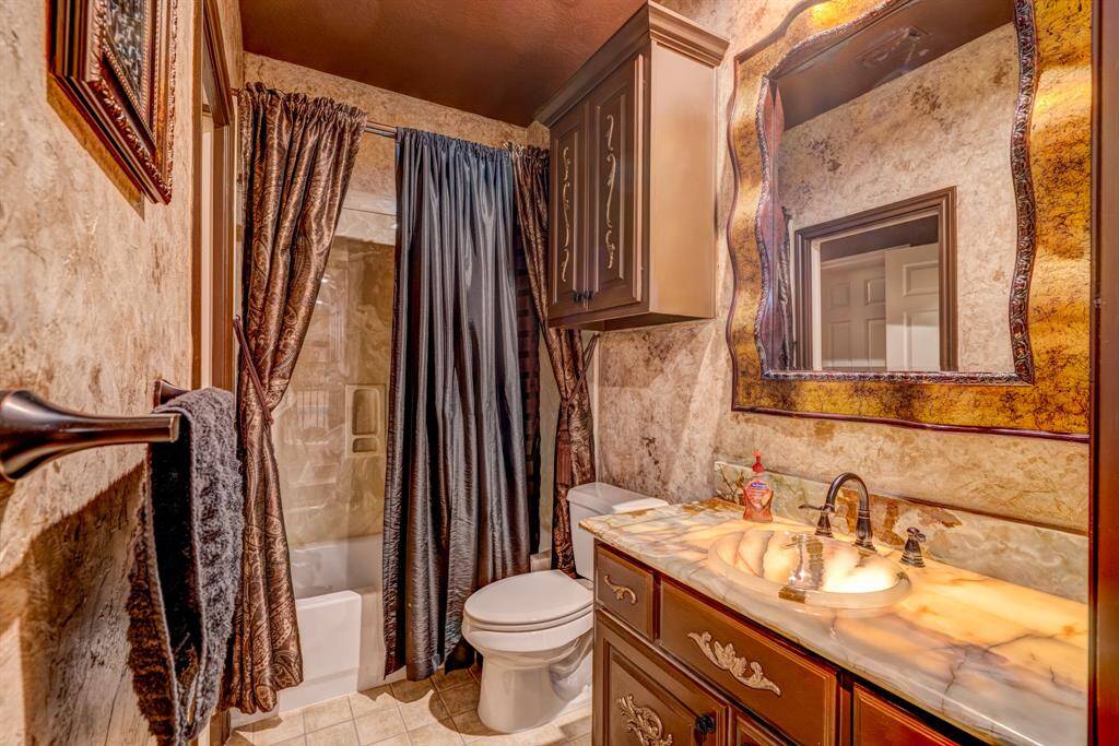 The fanciful guest bathroom includes a shower/tub combo, medicine cabinet, storage vanity, and a wall cabinet.