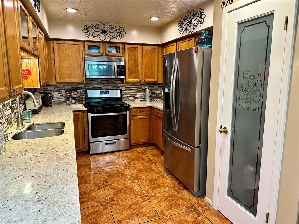 quartz counters, on trend tile backsplash, stainless appliances, a fancy pantry door and a breakfast bar.