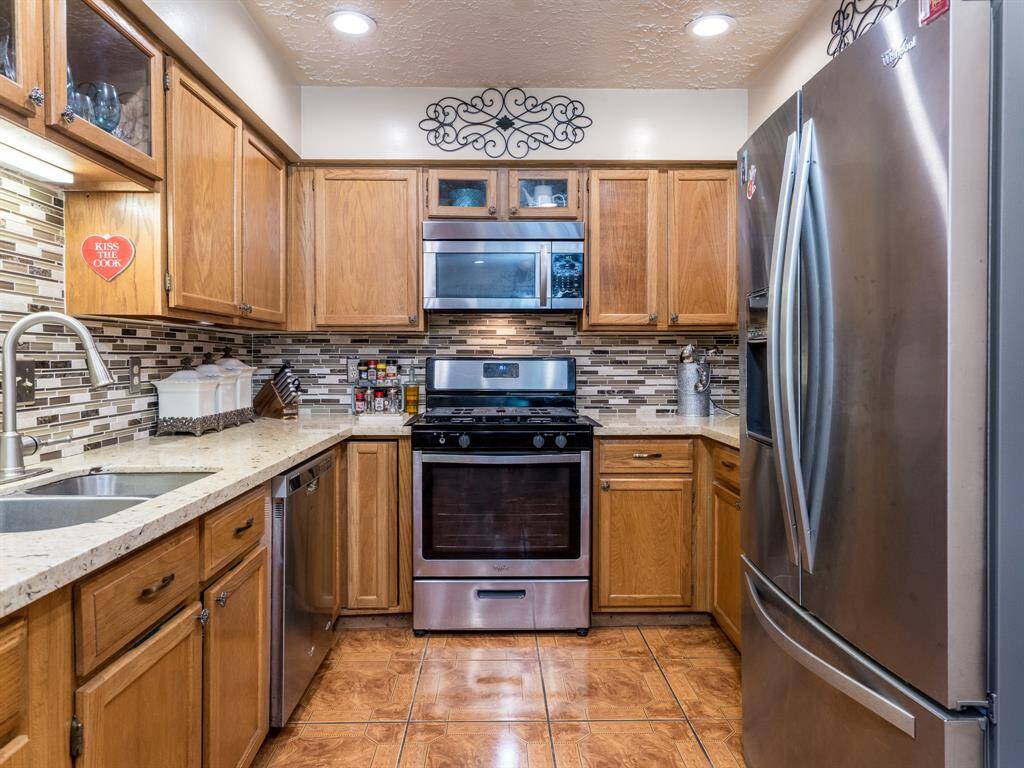 This updated galley kitchen includes quartz counters, on trend tile backsplash, stainless appliances, a fancy pantry door and a breakfast bar.
