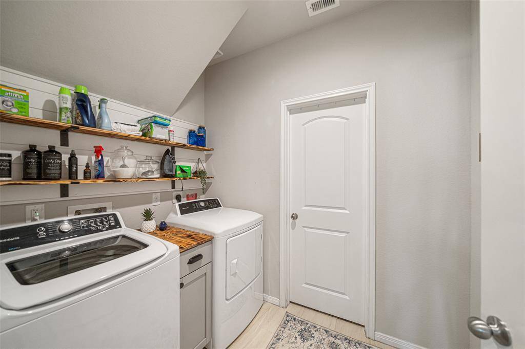 Now this is a great laundry room with custom shelving and cabinetry between the washer/ dryer that stay with the home.  Through that door is the Primary closet.