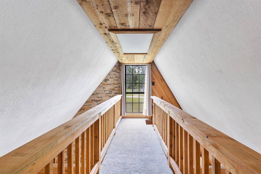A stylish catwalk overlooking the living room offers a dramatic vantage point to take in the home’s stunning architectural details, including the soaring stacked stone fireplace and rich natural wood accents.