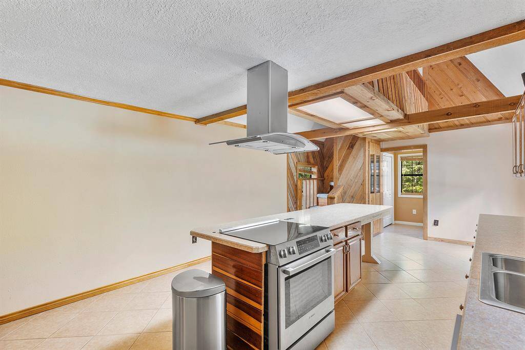 An alternate view of the kitchen reveals even more thoughtful design elements—a convenient utility room and half bath tucked just beyond, perfect for busy households. Look up, and you'll notice the catwalk at the top of the stairs, offering a striking architectural detail and a glimpse of the home's open, connected layout.