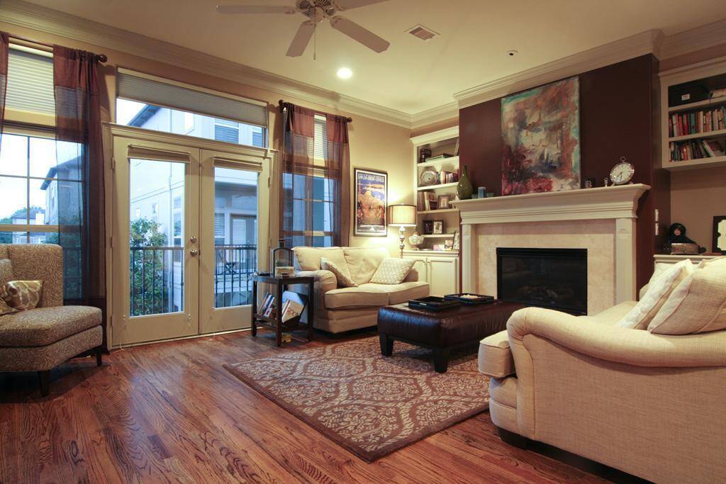 Living room with rich hardwood floors, fireplace, crown molding and fully adjustable window coverings that adjust from bottom and top