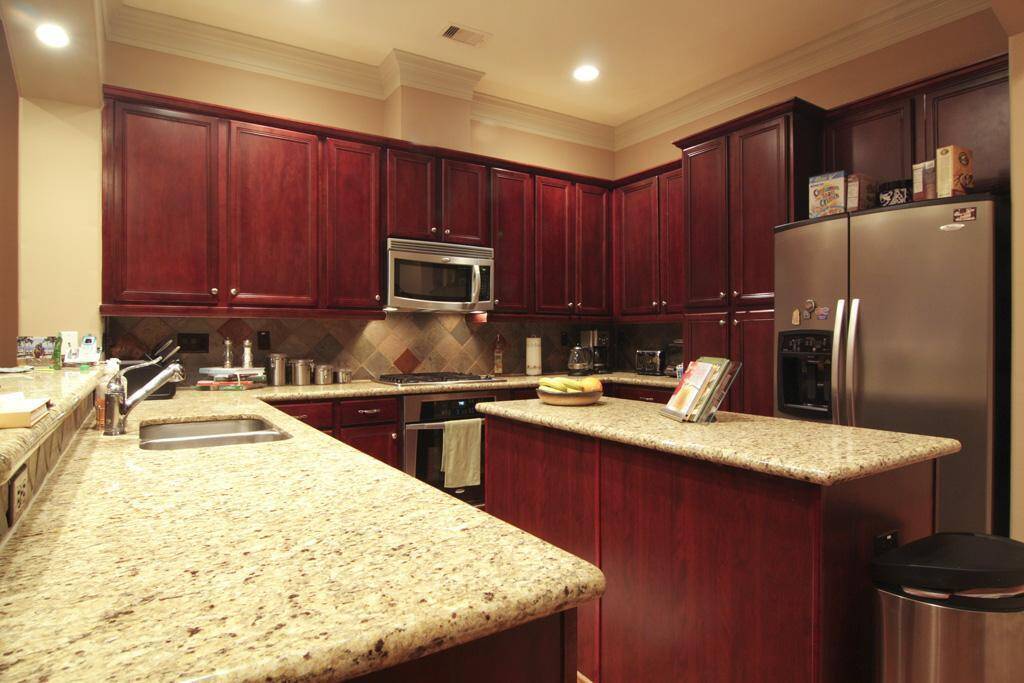 Island kitchen with granite counters, stainless steel appliances and rich hardwood cabinets