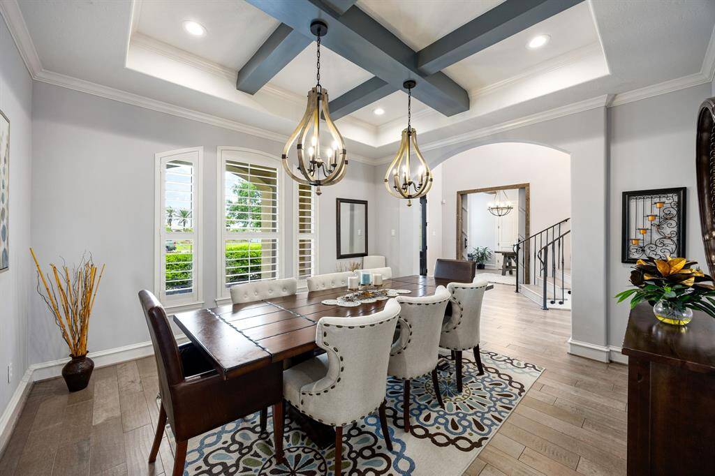 Formal dining with quality wood floors and light blue colored wooden beams on the ceiling with modern light fixtures