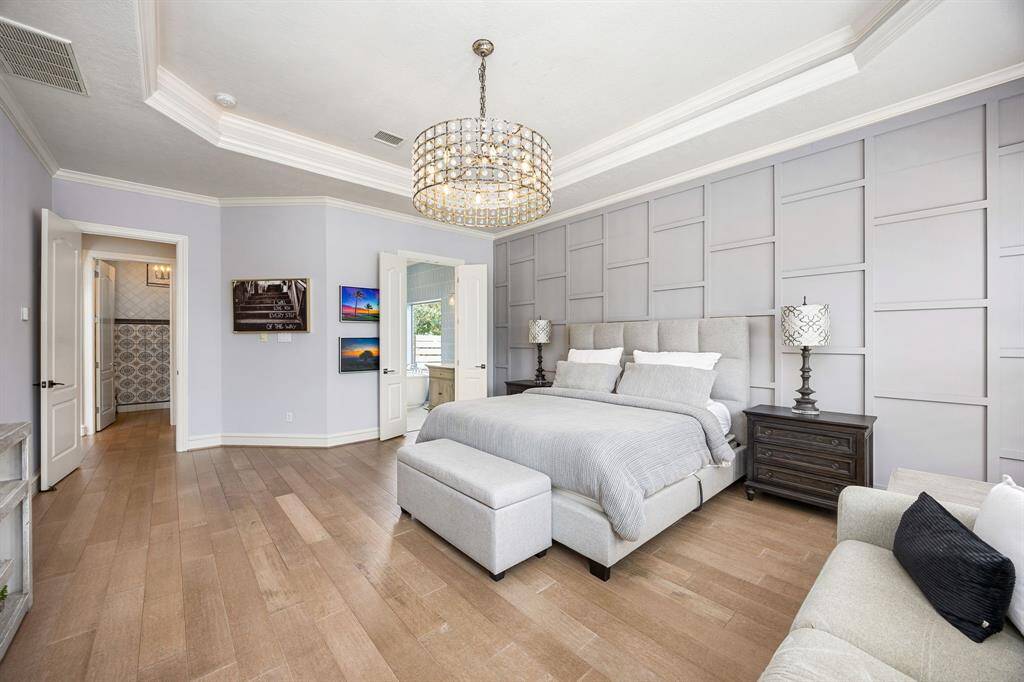 Modern luxurious light fixture brightens the primary room which has access to the back patio and pool to discretely step out for a night swim
