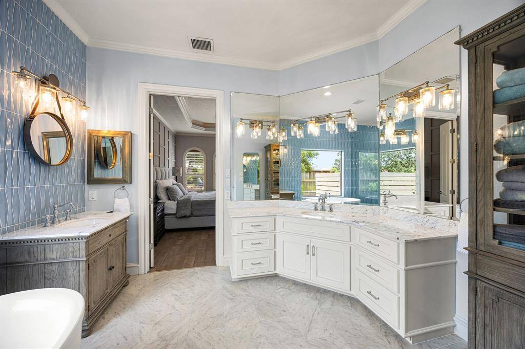 separate sinks and 3-sided mirror in primary bathroom with plenty of storage