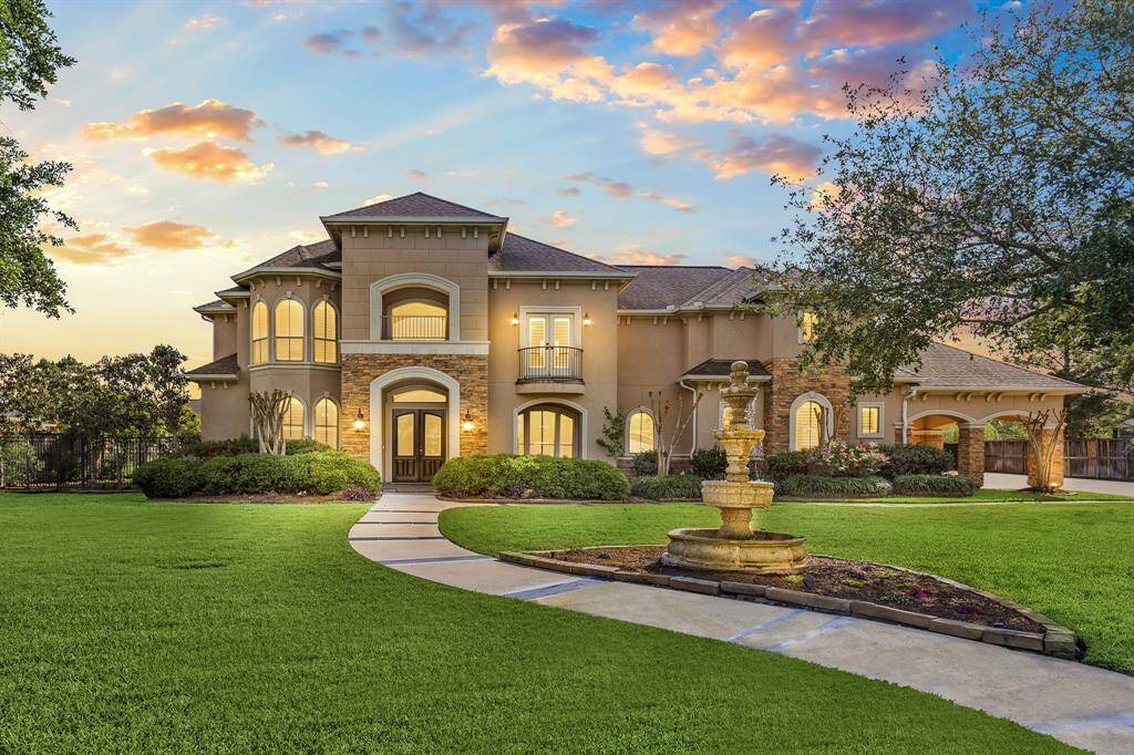 2 story home beautifully manicured landscape with stucco and stone facade