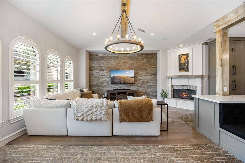 Family room with fireplace and accent brick wall and luxurious wooden chandelier
