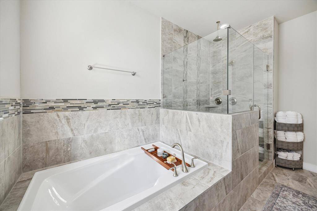 The primary bath features a spa-like jetted tub and a walk-in shower with a sleek, enclosed glass door.