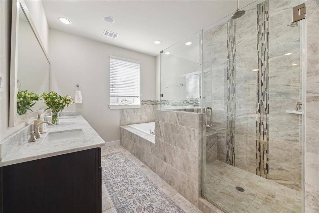 Another view of the primary bath showcasing the vanity with double sink and the spacious walk-in shower.