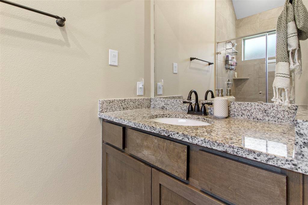 The primary bathroom features wood cabinets and a walk-in shower with tile surround and glass door.