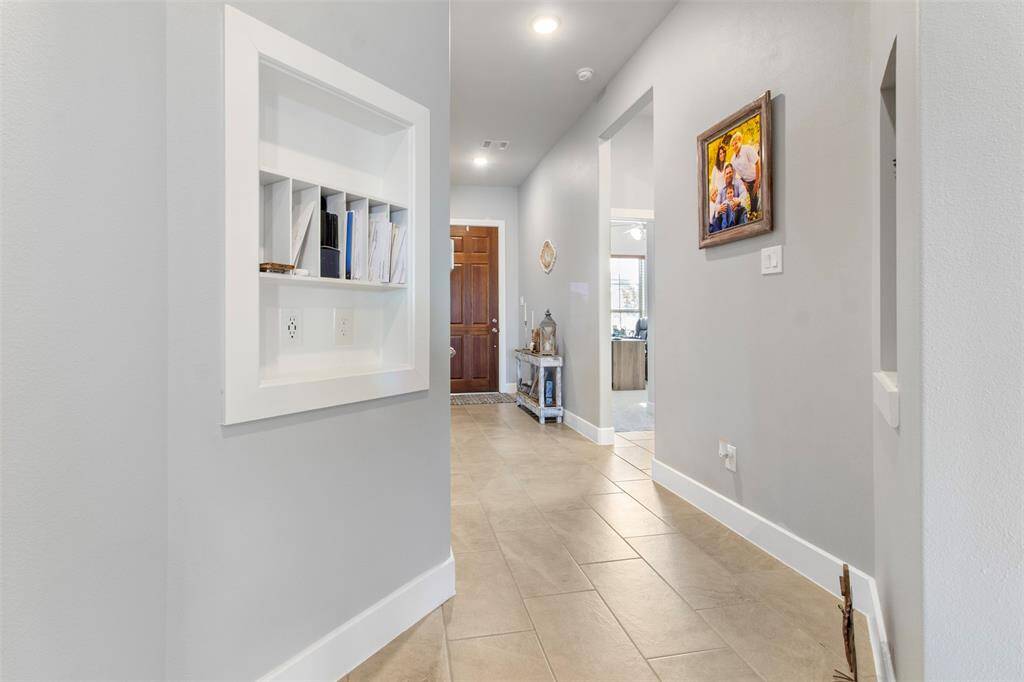 The elongated foyer has tile floors and recessed lighting.
