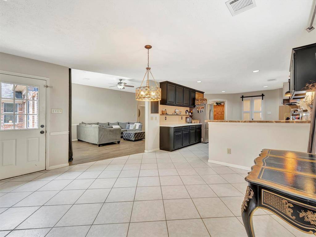 Take in the view of the open living room and kitchen from the den, showcasing a spacious, interconnected layout that enhances the flow of the home