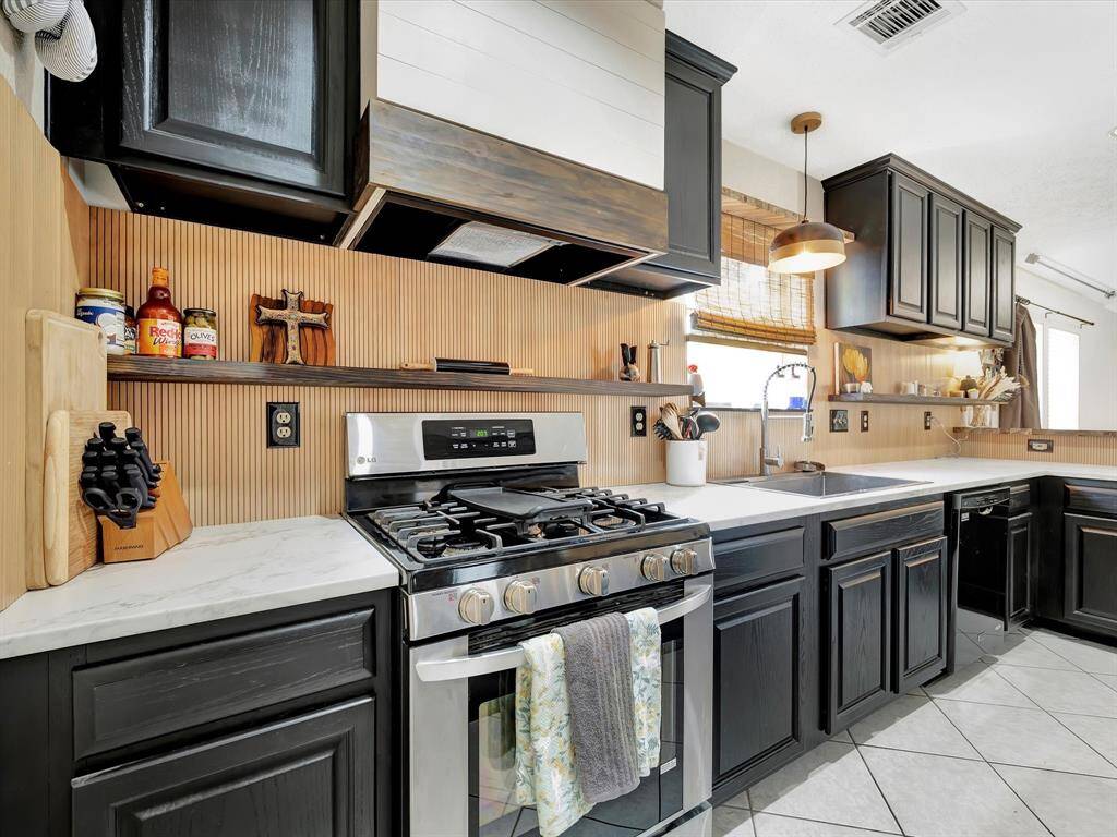 modern kitchen with a stainless steel range featuring 5 burners, set against sleek granite or quartz countertops. The space has matching stainless steel appliances, a stylish backsplash, and a polished wood or tile floor, creating a clean, contemporary look.