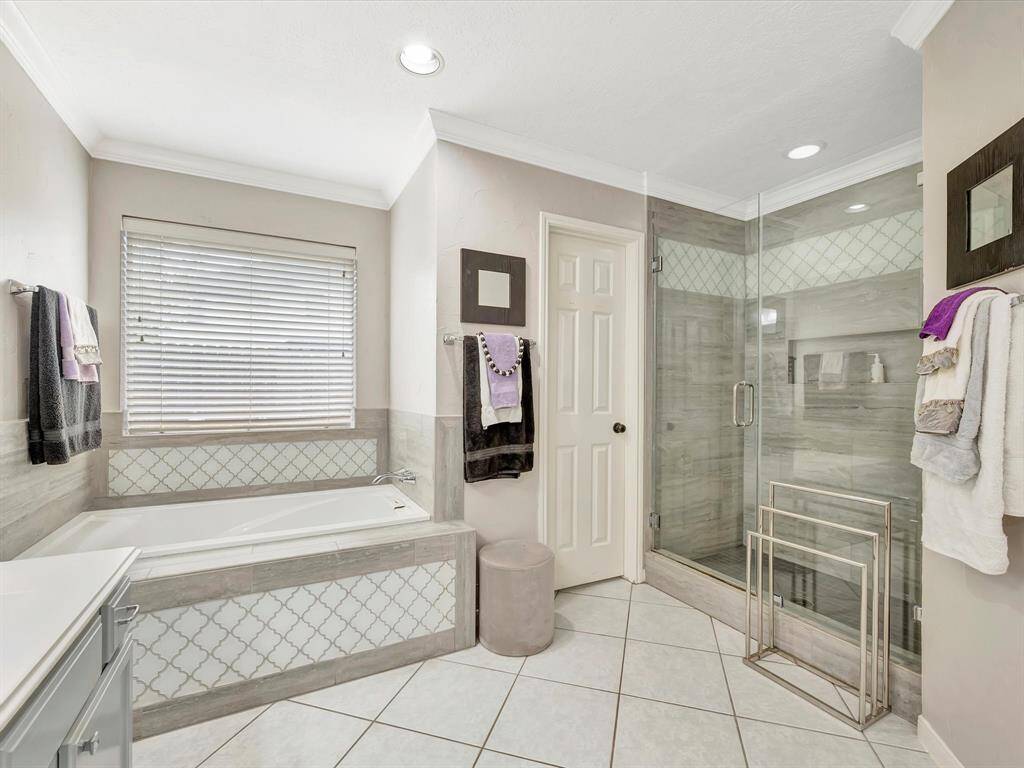 The bathroom features a stand-alone, separate shower with clean, modern lines, offering a refreshing and private experience. Adjacent to it, a luxurious soaker tub invites relaxation, creating a serene spa-like atmosphere. Together, these elements balance practicality and indulgence, enhancing the overall tranquility of the space.