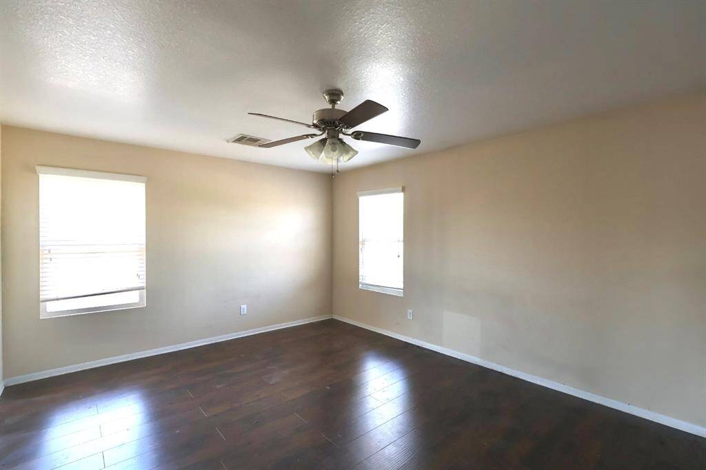 Upstairs secondary bedroom with fan and wood floors
