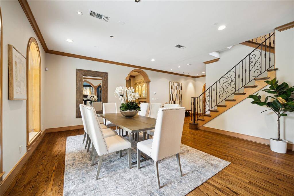 A sweeping staircase and detailed crown molding elevate the dining space with architectural grace and timeless style.