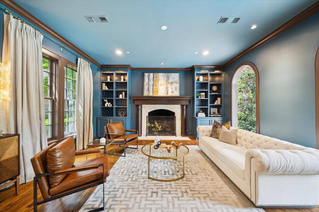 Sophisticated and stylish, this richly hued formal living room features a classic fireplace, custom built-ins, and poolside views.