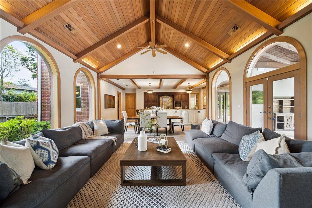 The dramatic great room features soaring wood-clad cathedral ceilings, walls of windows, and seamless connection to the chef’s kitchen.