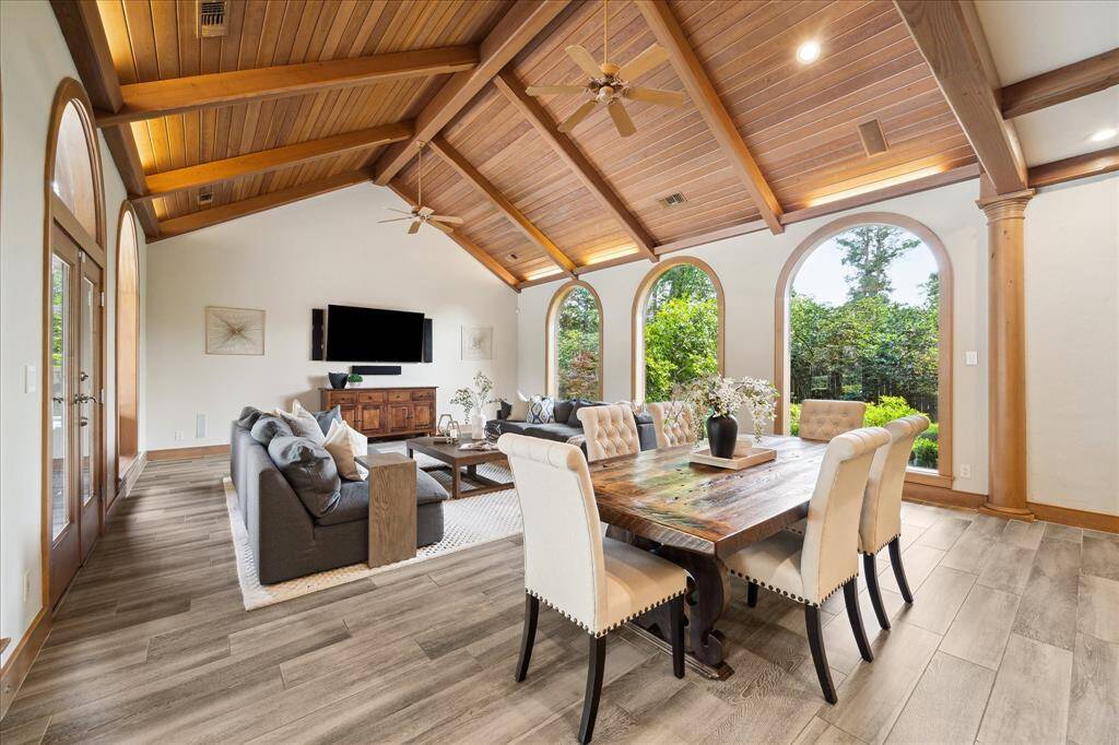 Soaring tongue-and-groove wood ceilings with beams and arched windows define this stunning living and dining space that opens to the backyard.