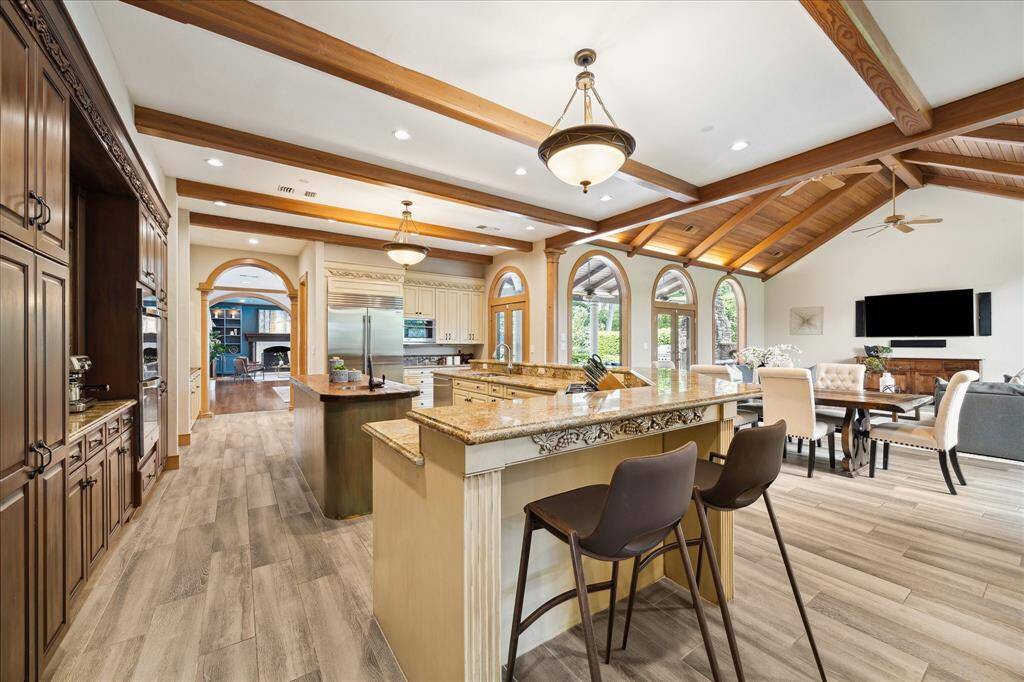 Expansive kitchen layout features Wolf & Sub-Zero appliances, hand-carved millwork, and warm wood beams that frame the space with character.