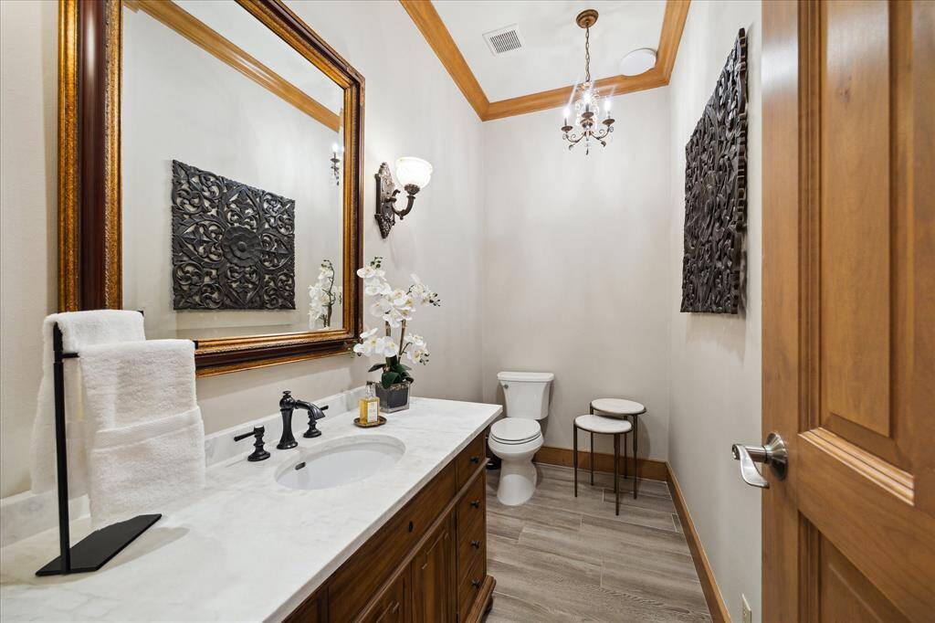 Elegant powder bath with marble-topped vanity, custom lighting, and crown molding—perfectly appointed for guests.