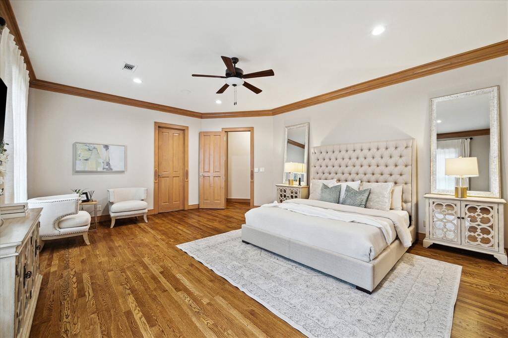 The serene primary suite is a private sanctuary, with wood flooring, generous seating area, and peaceful garden views.