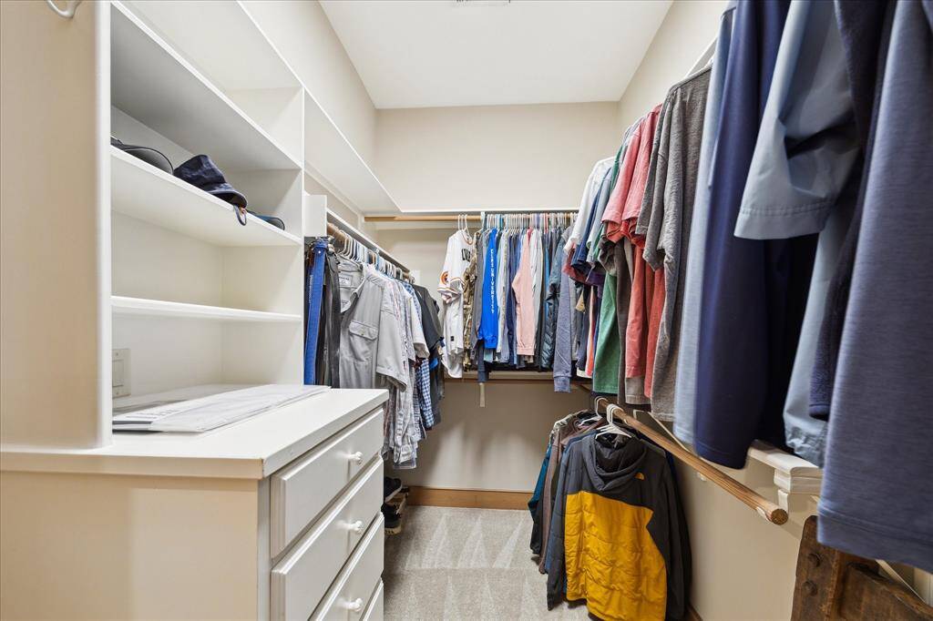 One of two custom walk-in closets in the primary suite, this space offers extensive hanging, shelving, and drawer storage to keep everything neatly organized.
