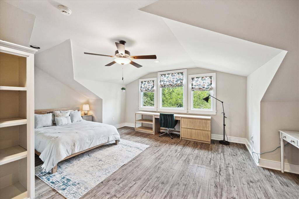 Flexible third-floor bedroom retreat with built-in desk, custom shades, and wood-look flooring—perfect as a guest suite or private home office.