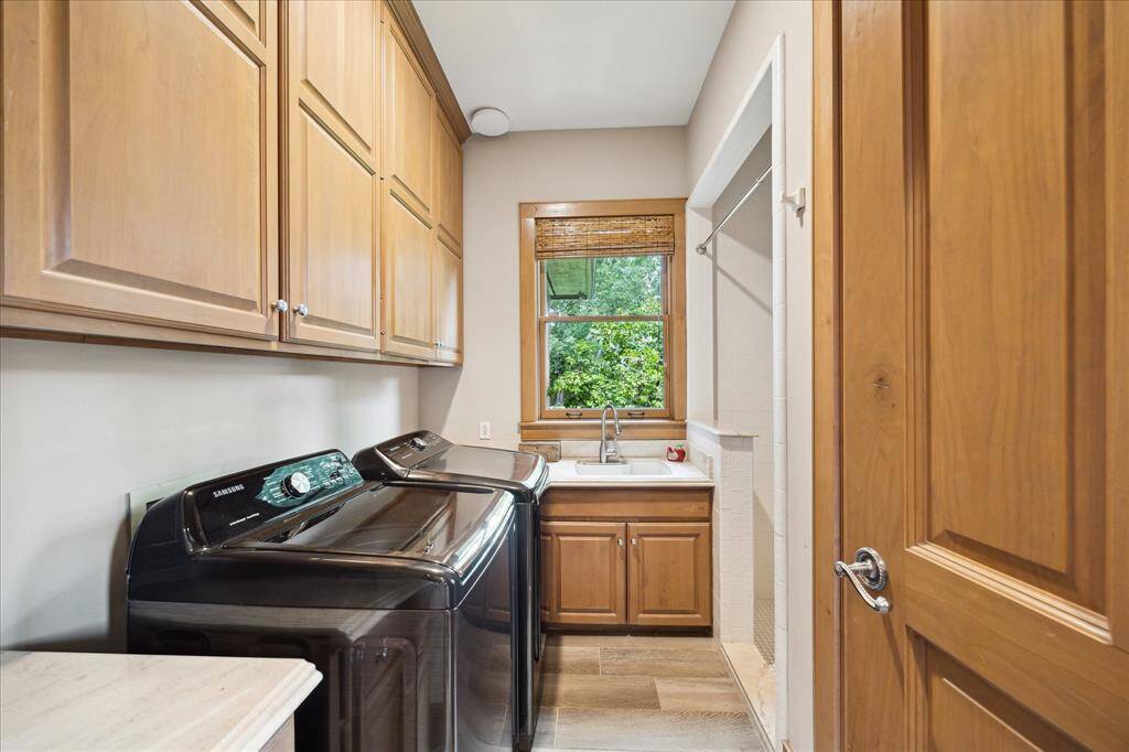 Functional meets charming in this utility room with built-in cabinetry, deep sink,  as well as shower and toilet making it another downstairs bath for cleaning up when coming in from a hard day's play