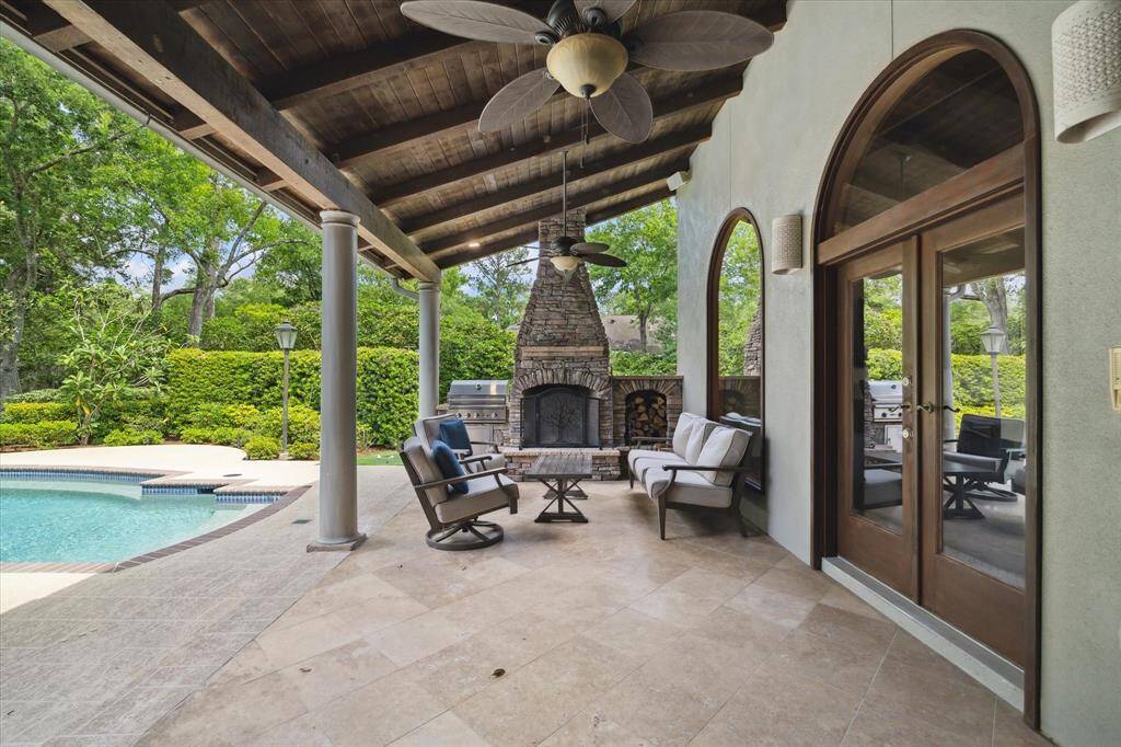 Covered outdoor living room with vaulted wood ceiling, fireplace, and grilling station—ideal for year-round entertaining.