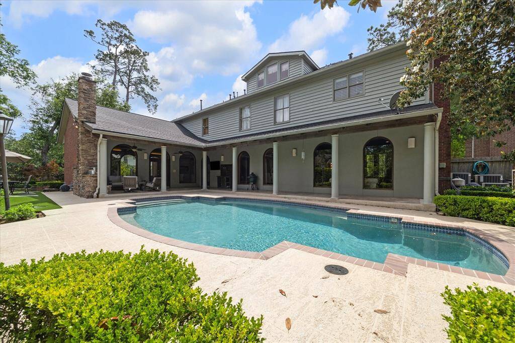 A wide view of the home’s expansive covered patio and arched loggia, designed for elegant entertaining poolside.